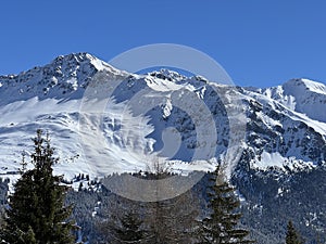 Beautiful sunlight and snow-capped alpine peaks above the Swiss tourist sports-recreational winter resorts