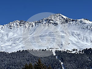 Beautiful sunlight and snow-capped alpine peaks above the Swiss tourist sports-recreational winter resorts