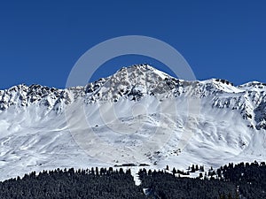 Beautiful sunlight and snow-capped alpine peaks above the Swiss tourist sports-recreational winter resorts