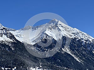 Beautiful sunlight and snow-capped alpine peaks above the Swiss tourist sports-recreational winter resorts