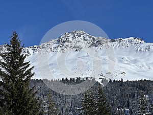 Beautiful sunlight and snow-capped alpine peaks above the Swiss tourist sports-recreational winter resorts