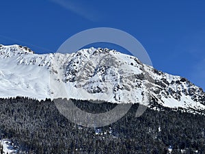 Beautiful sunlight and snow-capped alpine peaks above the Swiss tourist sports-recreational winter resorts