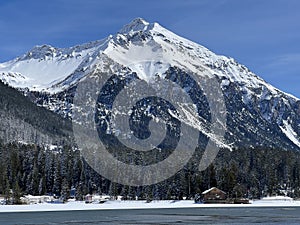 Beautiful sunlight and snow-capped alpine peaks above the Swiss tourist sports-recreational winter resorts