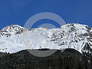 Beautiful sunlight and snow-capped alpine peaks above the Swiss tourist sports-recreational winter resorts