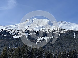 Beautiful sunlight and snow-capped alpine peaks above the Swiss tourist sports-recreational winter resorts