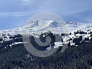 Beautiful sunlight and snow-capped alpine peaks above the Swiss tourist sports-recreational winter resorts