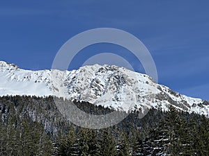 Beautiful sunlight and snow-capped alpine peaks above the Swiss tourist sports-recreational winter resorts