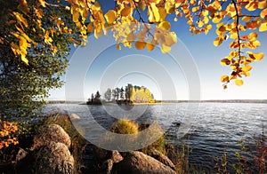 Beautiful autumn island in frame of golden leaves and stones. Fall in Vyborg bay, gulf of Finland