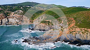 Beautiful sunny coastal landscape drone view. Ocean splashing rocky shoreline