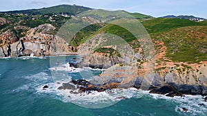 Beautiful sunny coastal landscape drone view. Ocean splashing rocky shoreline