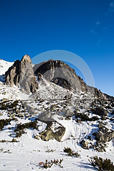 Beautiful sunny day on moutains in winter. Snow covered landscape with huge mountain peaks and clear blue sky on the background