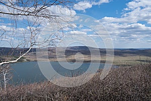 Beautiful sunny day at the top of the mountain. A wonderful view from the mountain to the lake with a spring landscape