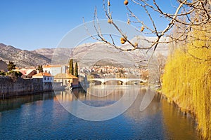 Beautiful sunny landscape, blue sky, yellow trees and ancient city reflected in river water. Bosnia and Herzegovina, Trebinje city