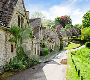 A beautiful sunny morning in Bibury, Gloucestershir, England, UK. Old street with traditional cottages