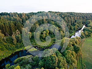 A beautiful sunny view of the forest, fields and river from above with a drone