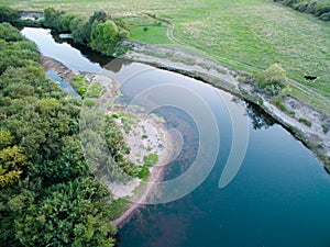 A beautiful sunny view of the forest, fields and river from above with a drone