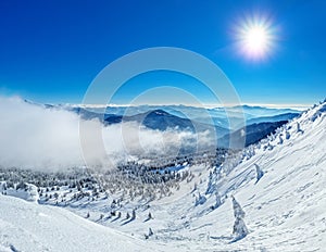 Beautiful sunny winter landscape in thÑƒ mountains. Mountain and fir trees covered with snow and clouds