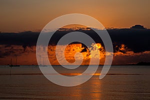 Beautiful sunrise on beach with boats in distance with clodscape