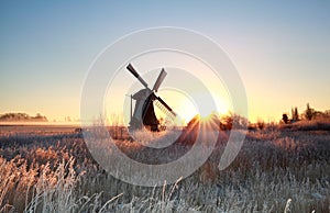 Beautiful sunrise behind windmill in winter