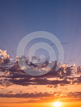 Beautiful sunrise with clouds of different colors and the rays of the sun against the blue sky