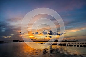 A beautiful sunrise with cloudy sky on the beach.