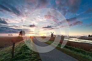 Beautiful sunrise on dutch farmland with windmill