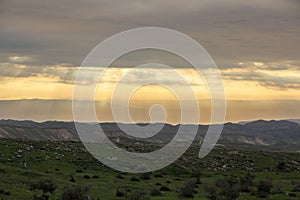 Beautiful sunrise of Judean Desert wadi, with sun rays breaking through clouds over the dry riverbed of Nahal Dragot