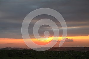 Beautiful sunrise of Judean Desert wadi, with sun rays breaking through clouds over the dry riverbed of Nahal Dragot