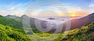 Beautiful sunrise in mountains with white fog below panorama