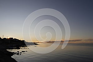 Beautiful sunrise over an arctic lake with fog on the horizon and sun peaking over buildings