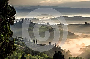 Beautiful sunrise over misty landscape of Italy. Early morning over rural area with gardens, fields in Tuscany province