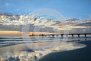 Beautiful sunrise over ocean horizon and pier.