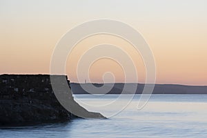 Beautiful sunrise over Pentewan Sands in Cornwall with pastel sky and long exposure ocean