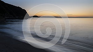 Beautiful sunrise over Pentewan Sands in Cornwall with pastel sky and long exposure ocean