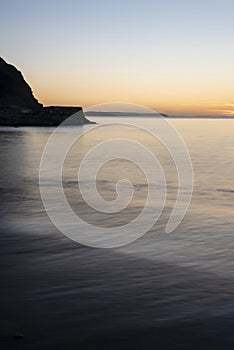 Beautiful sunrise over Pentewan Sands in Cornwall with pastel sky and long exposure ocean