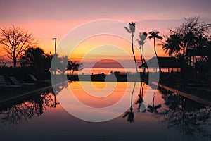 Beautiful Sunrise with silhouette coconut palm tree and swimming pool in beautiful luxury hotel resort