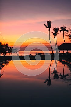 Beautiful Sunrise with silhouette coconut palm tree and swimming pool in beautiful luxury hotel resort