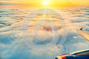 Beautiful sunrise sky above clouds with aircraft wing and engine. View from airplane window