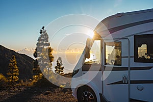 Beautiful sunset in background and modern camper van parked in the nature to enjoy freedom and vanlife alternative lifestyle.