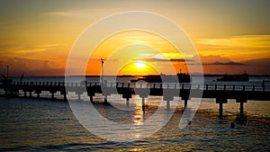 Beautiful sunset on the beach with bridge silhouette