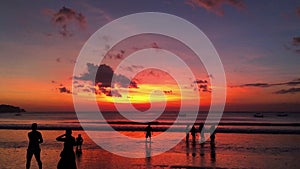 Beautiful sunset on the beach of the Jimbaran village with silhouettes of people. Bali, Indonesia