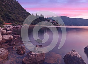 Beautiful sunset on the beach in Montenegro with long exposure effects in the sea. Beach landscape with city lights in the