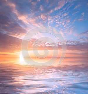Beautiful sunset, bright sun and soft, multicolored clouds against the background of the sea