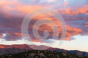 Beautiful sunset casts purple and orange colors on clouds and mountains near Santa Fe, New Mexico
