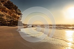 Beautiful sunset with cliff and rocky beach on deserted Namibe beach. Africa. Angola