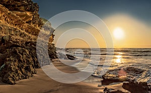 Beautiful sunset with cliff and rocky beach on deserted Namibe beach. Africa. Angola