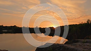 Beautiful sunset and cloudy sky over a forest lake at evening in vacation, showing the gentle lake ripples and waves at