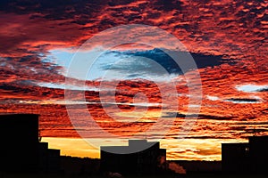 Beautiful sunset with fallstreak hole in red fiery sky and a buildings silhouette photo