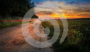 A beautiful sunset, fields, forest and road.