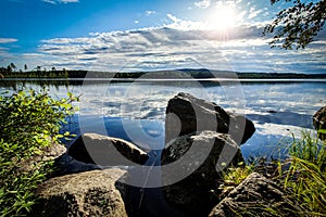 Beautiful sunset in forest mountain landscape. Lake and rocks in foreground. Angersjon between Hudiksvall and Soderhamn in Sweden